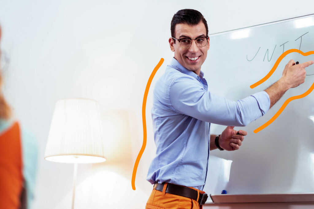 Project management. Man pointing at a white board and smiling