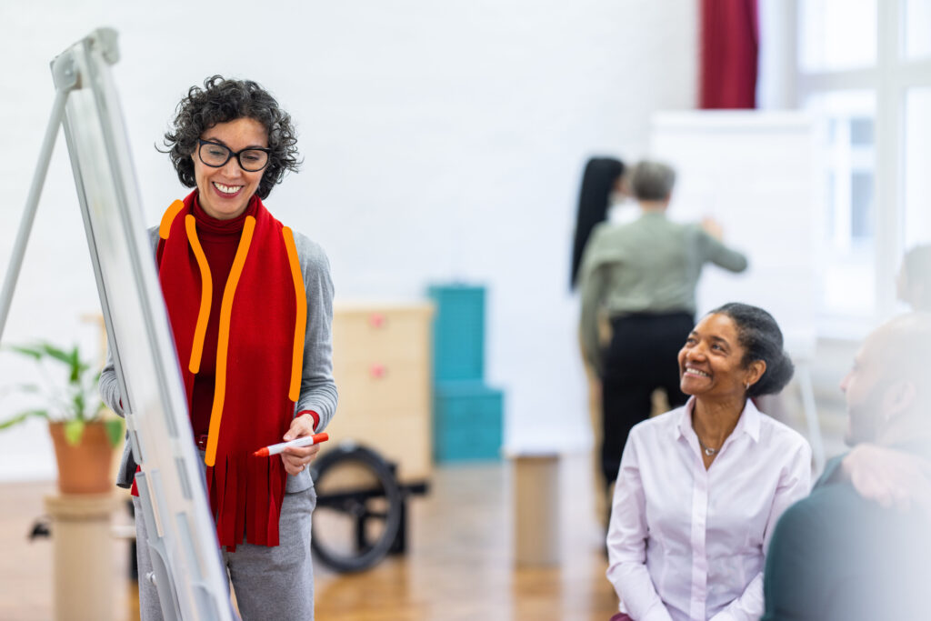 Project Management
Mature businesswoman writing on a flipchart and discussing a project with team in a workshop. Female giving presentation on flip chart to colleagues in workshop.